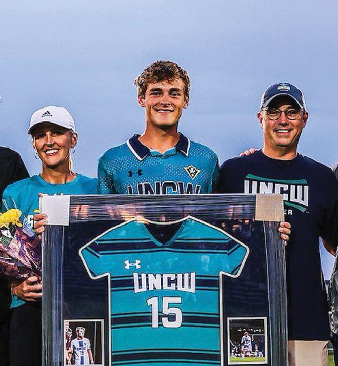 Jake Shannon with parents holding framed UNCW jersey