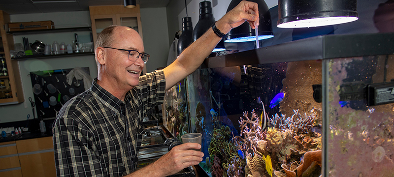Distinguished Professor Joseph Pawlik in classroom with aquarium