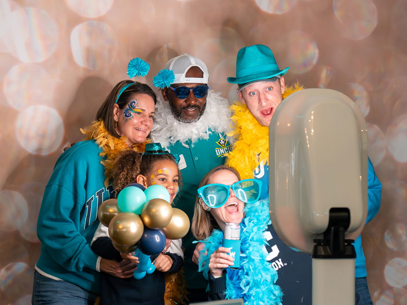 Family and Friends taking a photo with UNCW gear
